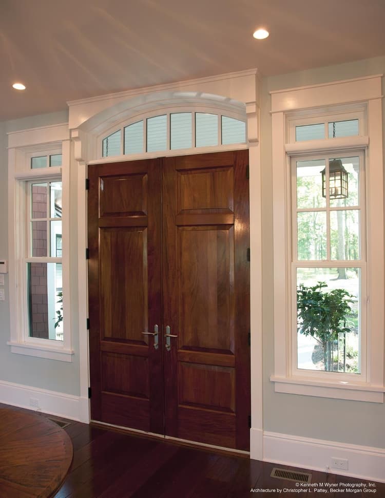 Heritage Series inswing entrance door with segment head transom and Sterling double hungs with transoms
