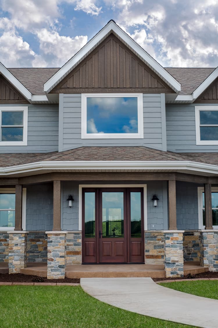 Ultra Series inswing door with raised panels and sidelites, Forgent Series double hungs and direct set windows, Extruded aluminum clad exterior door and sidelites with custom Decoral National Walnut finish, Glastra exterior windows in Cloud, Dallas hardware in Matte Black